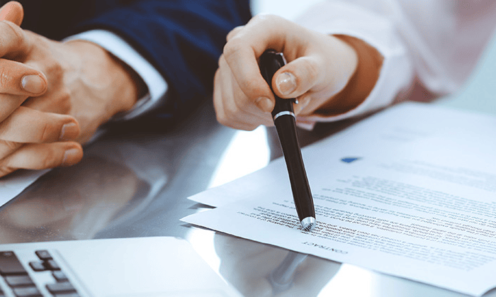 Geschäftsmenschen bei Finanzgespräch mit Dokumenten und Stift.