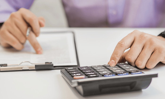 Person berechnet Abschreibung mit Taschenrechner und Notizen.